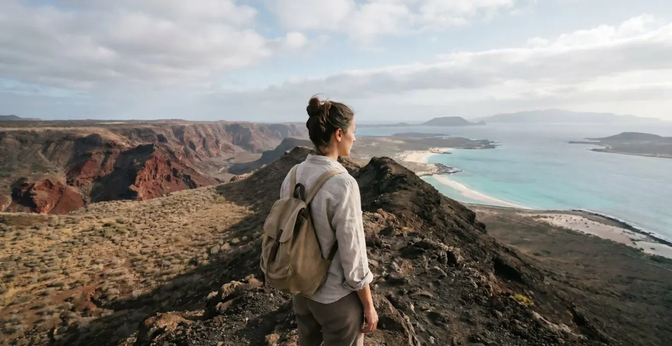 Voyageuse française contemplant un paysage volcanique contrasté avec une plage turquoise au loin sur une île du Cap-Vert