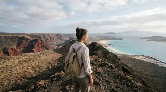 Voyageuse française contemplant un paysage volcanique contrasté avec une plage turquoise au loin sur une île du Cap-Vert